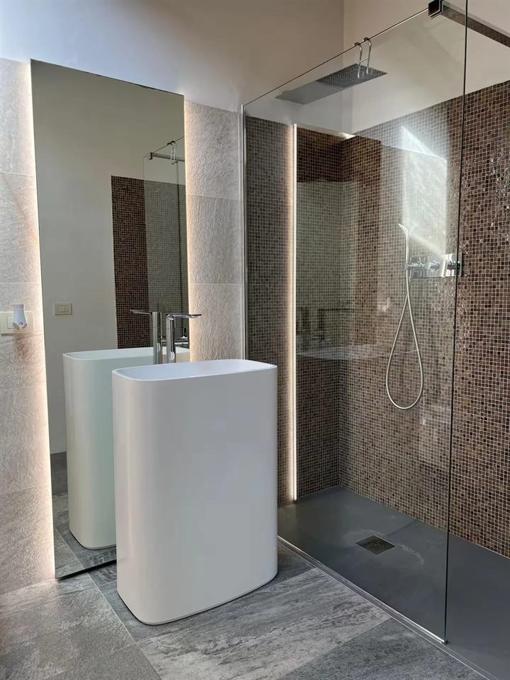Bagno di Domus Cerchio 19: lavabo freestanding bianco, specchio retroilluminato, doccia con mosaico